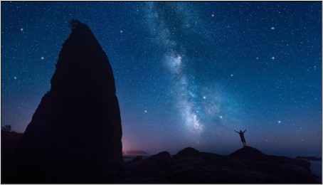 Silhouette of a person under a starry night sky.